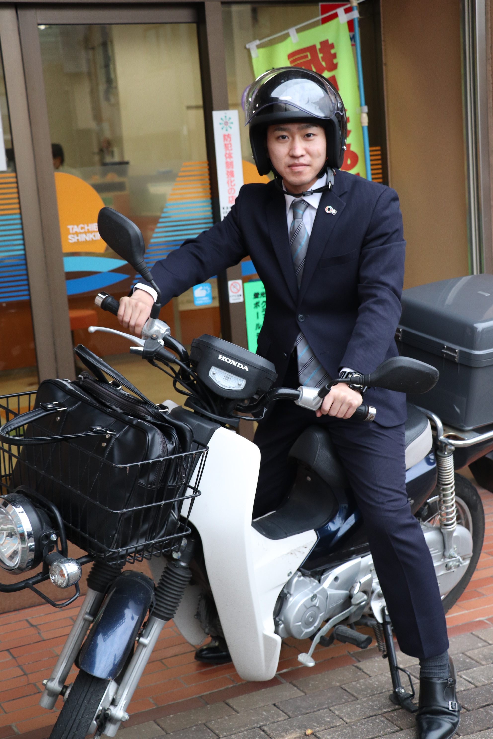 写真：原付バイクの横に立っている男性職員